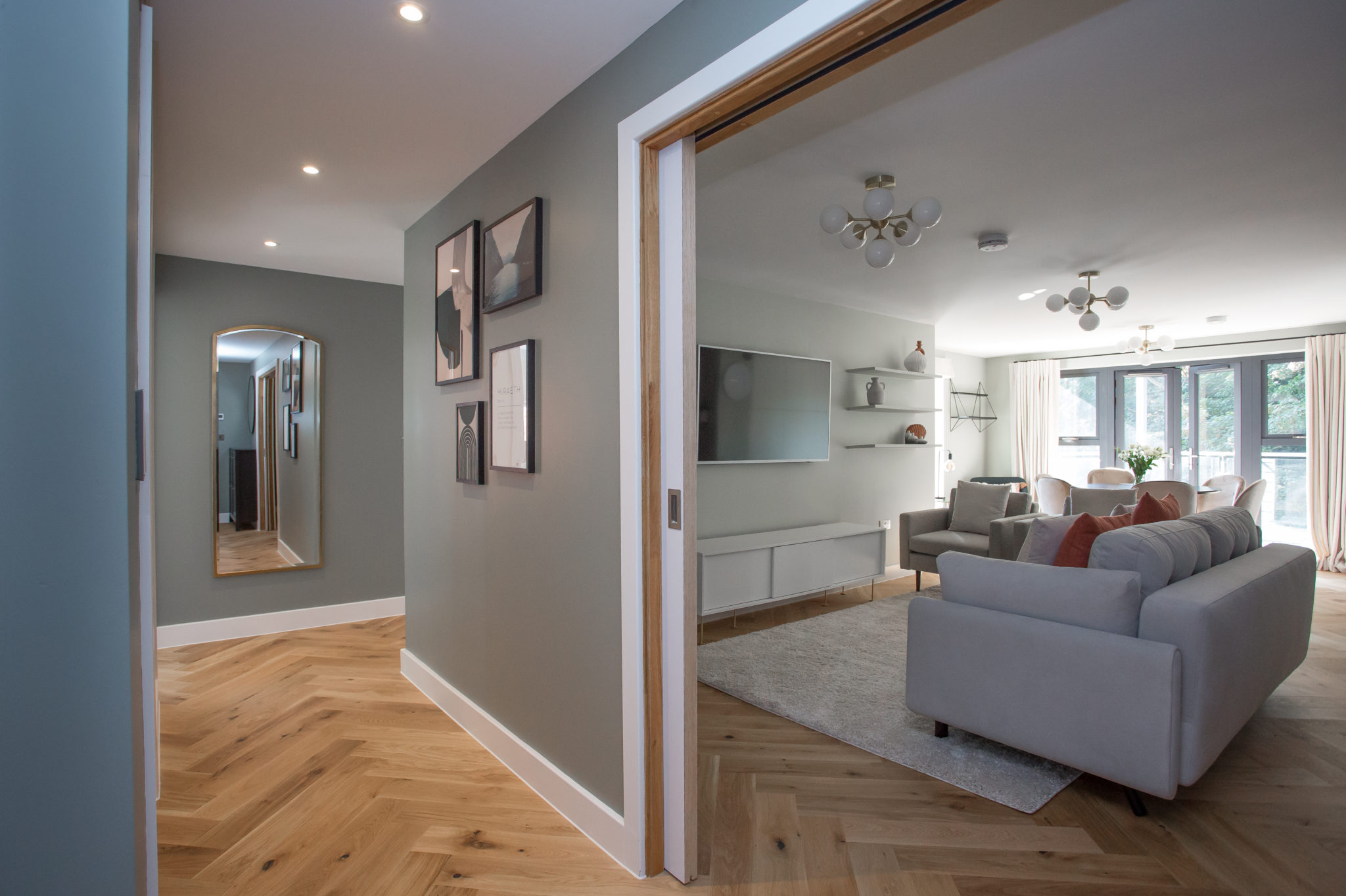 shot of hallway, looking into sitting area; walls are muted and there are artwork on the walls. 