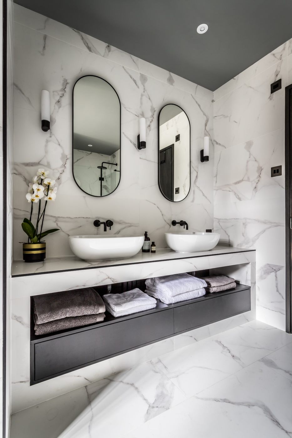 hotel luxe bathroom with marble vanity space and modern wall lighting 