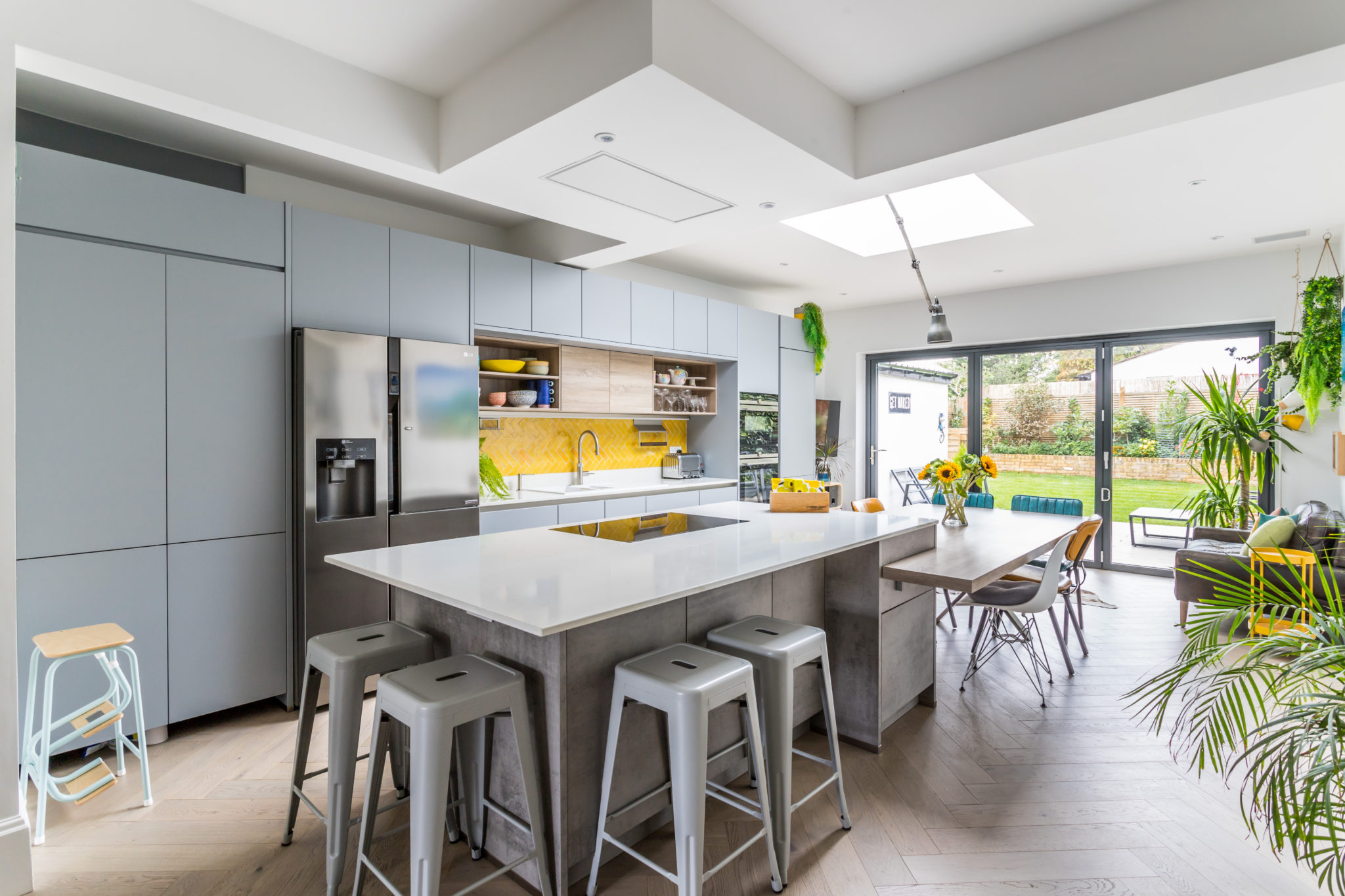 image shows a bright and spacious family kitchen with yellow details and a kitchen island 